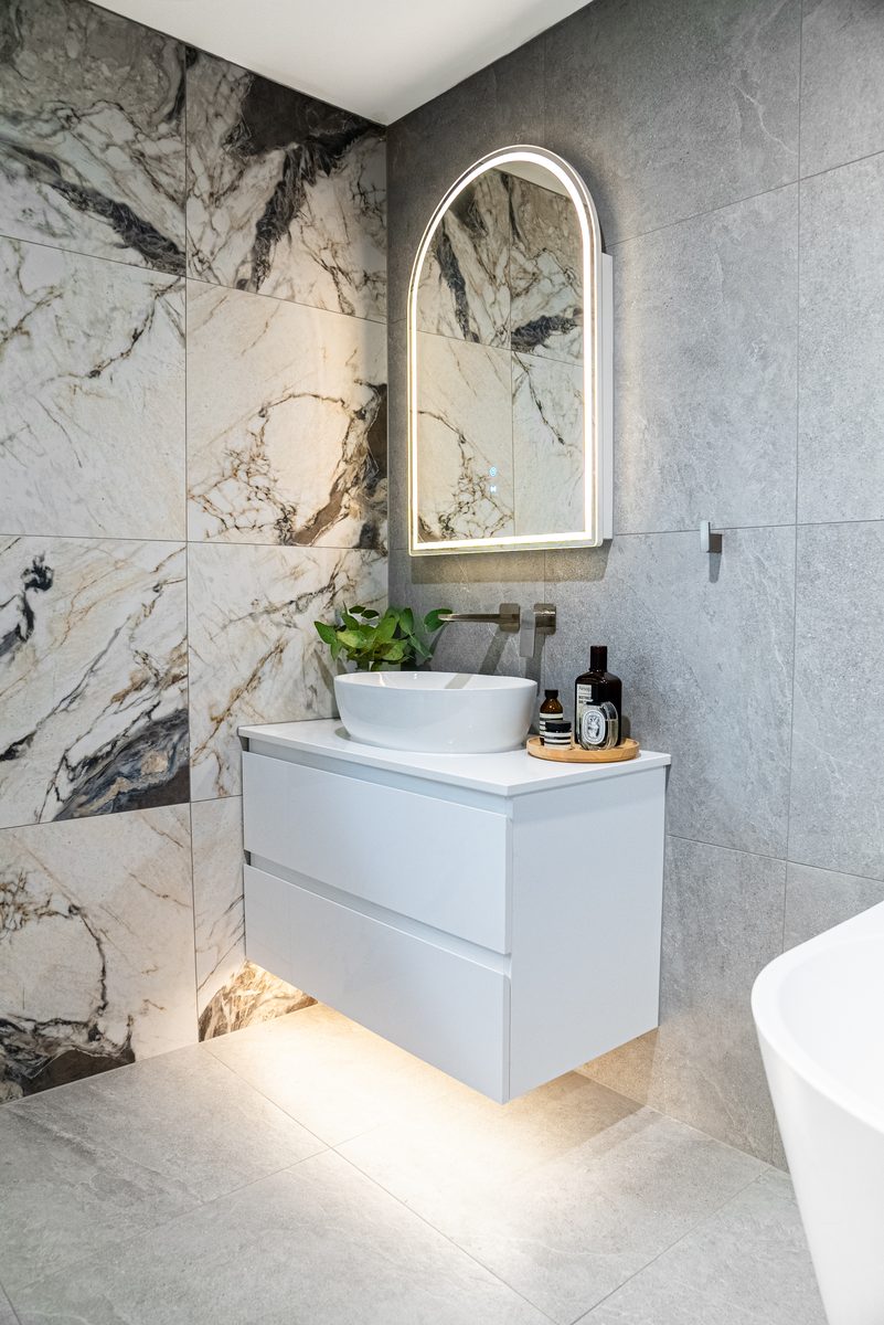 Bathroom with arched mirror and stone tiling