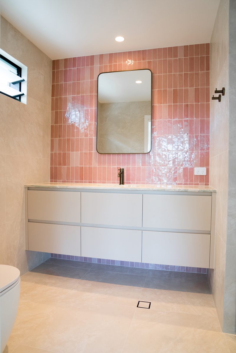 Bathroom vanity with pink tiled splashback